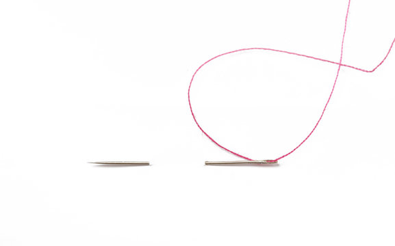 Sewing needle with red thread through the white background