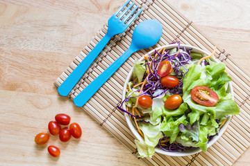 Dietary salad with fresh vegetables (tomato, cucumber, Chinese cabbage, red onion and cranberries). Top view wood backgtound