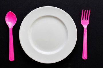 Empty plate with spoon and fork on black background