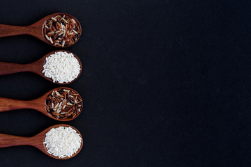 collection of grains in wooden spoon on black background.