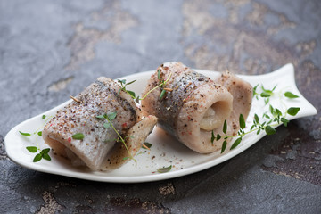 Herring rolls with fresh thyme and spices served on a white plate, selective focus, horizontal shot