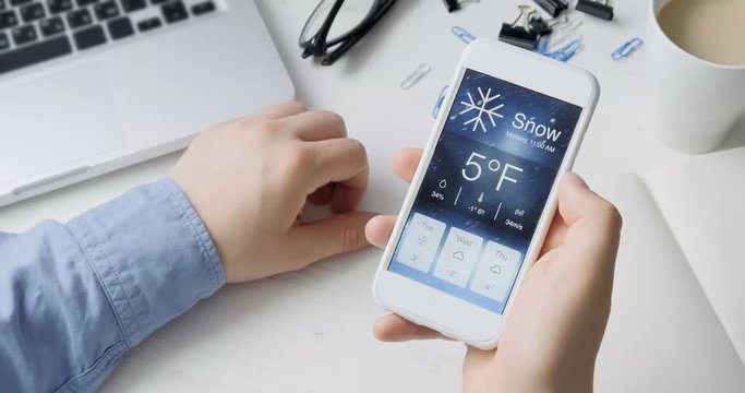 Checking wather using smartphone app. Snowy and cold
