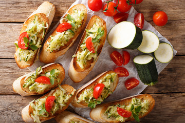 Italian bruschetta with zucchini and tomatoes close-up and ingredients. horizontal top view