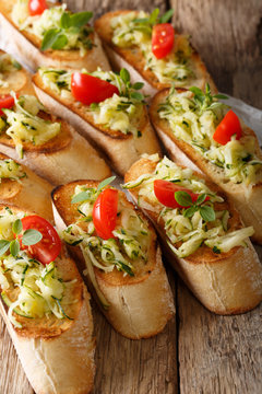 Tasty bruschetta with grated zucchini and tomatoes close-up. vertical