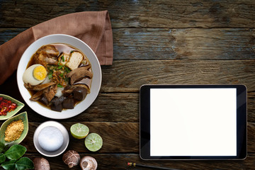 Paste of rice flour with pork, Blank screen tablet and Chinese roll noodle soup over wooden table.