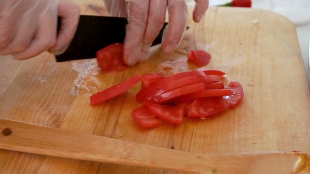 Cutting tomato on wooden board, closeup
