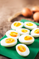 Hard boiled eggs, sliced in halves on cutting board wooden background close up.