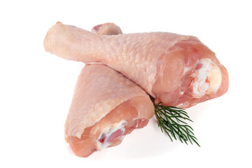 Two raw chicken drumsticks with a sprig of dill isolated on white background