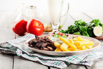 Grilled meat with French fries and fresh vegetables