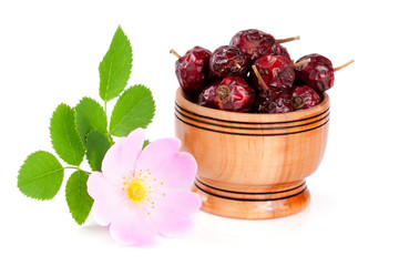 Rosehip flowers with leaf and rosehip berries in a wooden bowl isolated on white background