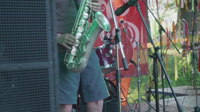 Man plays sax on stage during busked concert