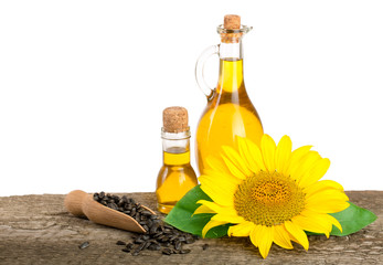 Sunflower oil, seeds and flower on wooden table with white background