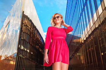 Portrait of gorgeous woman in pink dress outdoors at urban background with skycrappers. Concept of street vogue.