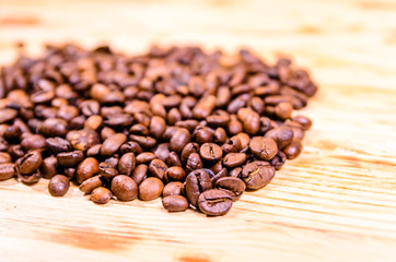 Pile of the roasted coffee beans on wooden table