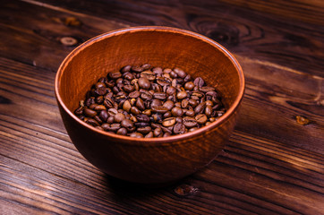 Roasted coffee beans in bowl on wooden table