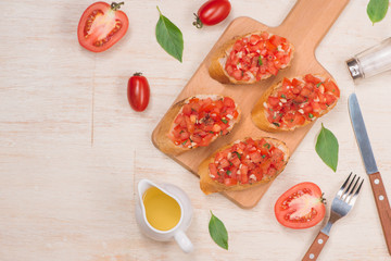 Preparing delicious Italian tomato bruschetta with chopped vegetables, herbs and oil