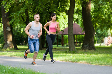sport woman and man running together in a park in summer