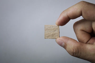 Hand holding small wood cube.