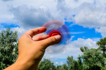 Red fidget spinner rotates in female hand