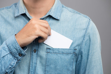 Young man who takes out blank business card from the pocket of his shirt