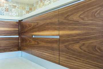 Modern home interior. Texture of the wood of the facades of the modern kitchen are made from walnut veneer. European furniture, design, technologies. Fine design.  Refinishing kitchen cabinets. 