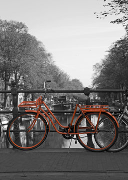Black and white view of Amsterdam with orange bicycle