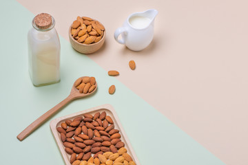 Almonds and milk bottle on light background. Almond nuts in spoon.