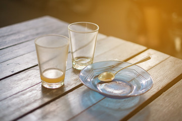 Empty glass of hot tea in with saucer and spoon on wooden table vintage tone, shallow focus.
