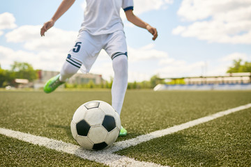 Boy Kicking Ball on Football Field