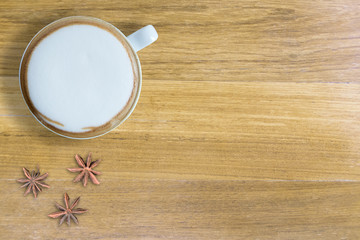 Hot cappuccino and anise on brown table. copy space