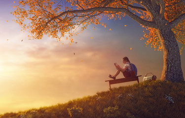 child reading the book near tree