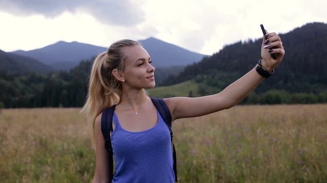 Young beautiful girl doing selfie in the mountains