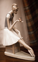 Thoughtful young girl (ballerina) holding a bird in her hand. Old figurine at flea market in Paris....
