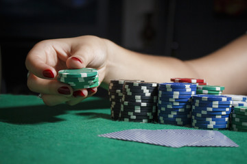 The girl at the poker table is holding chips