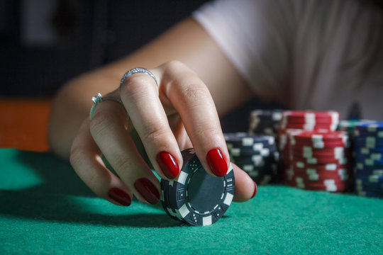 The girl at the poker table is holding chips