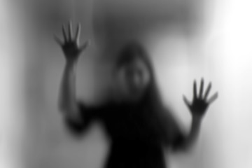 Horror woman behind the matte glass in black and white. Blurry hand and body figure abstraction