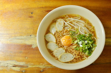 boiled instant noodle topping egg yolk and slice fish line in spicy soup
