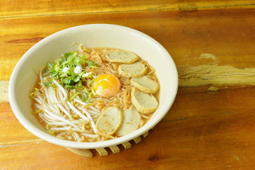 boiled instant noodle topping egg yolk and slice fish line in spicy soup
