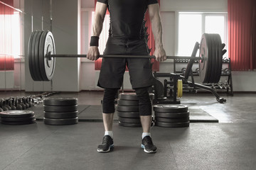 Young man doing deadlift exercise at gym.
