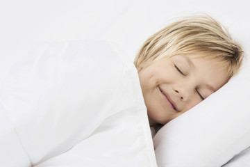 Boy sleeping in bed and smiling