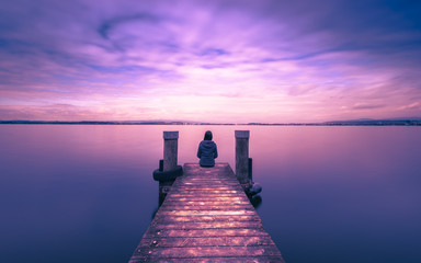 Mystical world. A lone figure on the pier of the lake. Long exposure. - 166871886