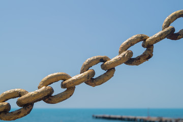 Old metal gold chain on the beach background in the sunlight