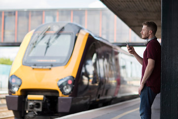 Man At Railway Station Using Mobile Phone On Platform