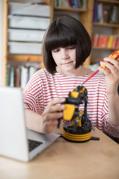 Teenage Girl Building Robotic Arm At School