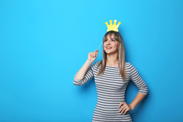 Portrait of young woman with crown on blue background