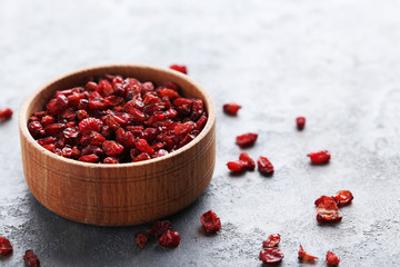 Pile of dry barberries in bowl on grey wooden table