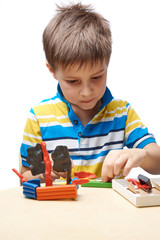 Kid is sculpting a ship with colorful modelling clay.