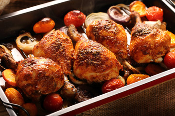 Roasted chicken legs with vegetables on wooden background