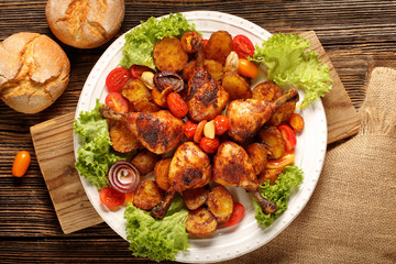 Roasted chicken legs with baked potato on the plate