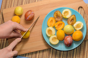 Hand cuts fruit on a wooden board